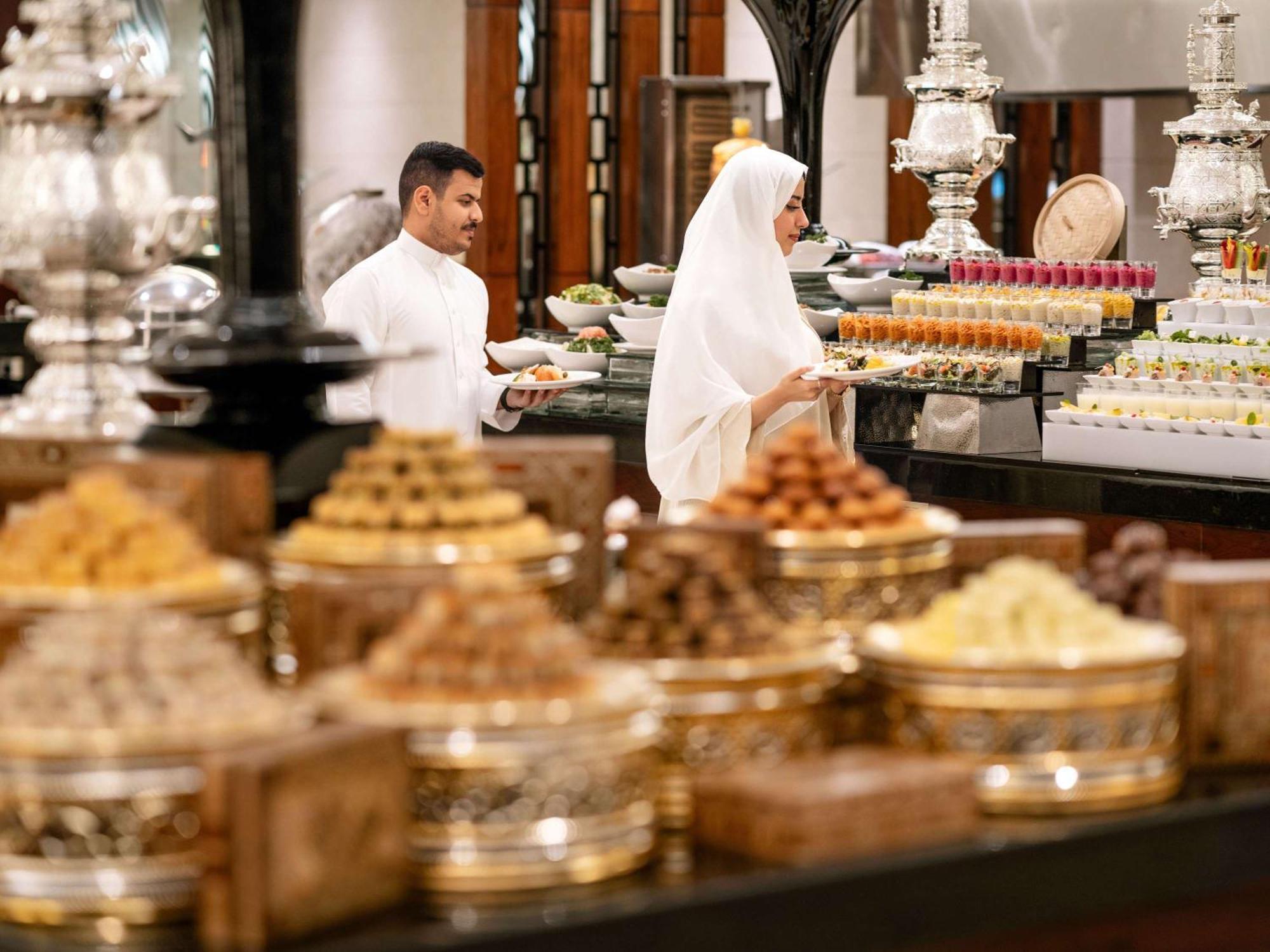 Swissotel Al Maqam Makkah Mekka Eksteriør billede The photo depicts a beautifully arranged display of traditional desserts and sweets. In the foreground, there are multiple decorative containers filled with various sweets, showcasing an assortment of vibrant colors and textures. In the background, t