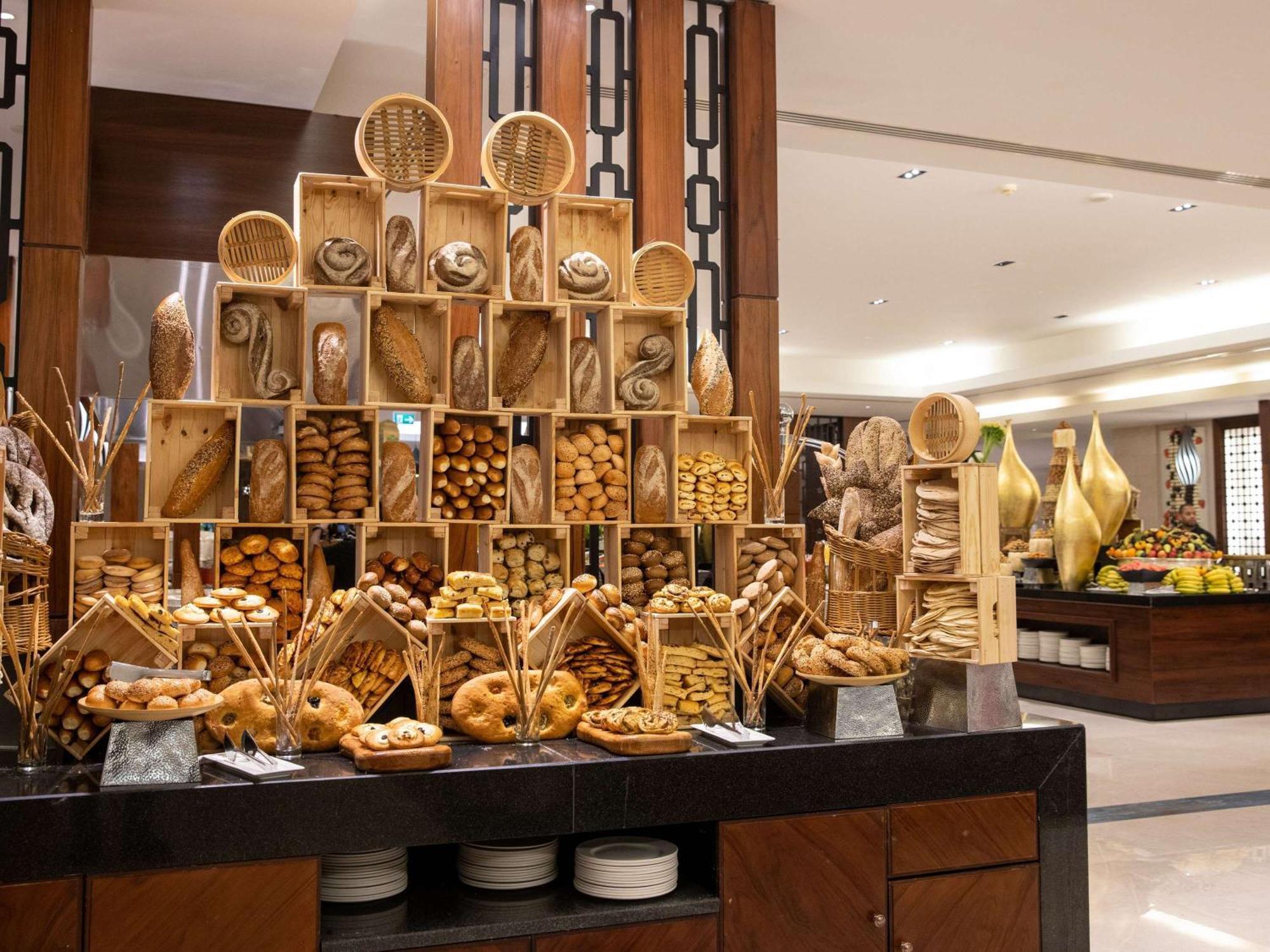 Swissotel Al Maqam Makkah Mekka Eksteriør billede The photo features a beautifully arranged display of various types of baked goods and snacks. There's an impressive tower made of bamboo baskets filled with an assortment of bread, cookies, and pastries. The items are attractively presented, showcasi