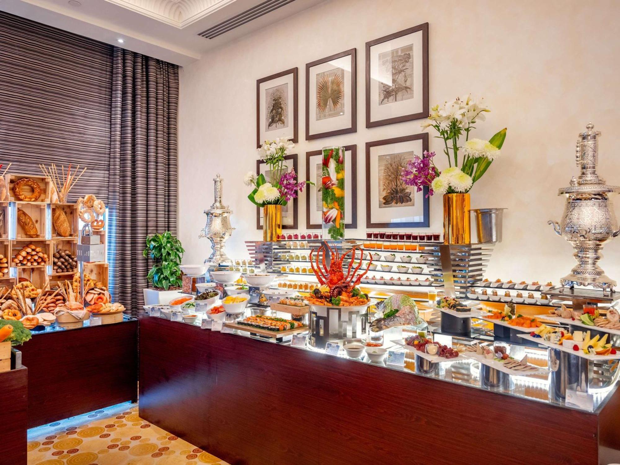 Swissotel Al Maqam Makkah Mekka Eksteriør billede The image depicts an elegantly arranged buffet display, featuring a variety of culinary offerings. There are multiple tiers of food items, including colorful fruits, desserts, and savory dishes. The presentation includes decorative elements such as f